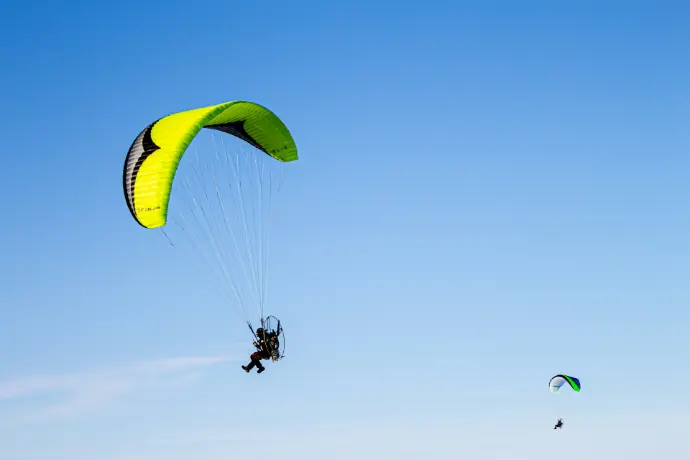 person in green parachute under blue sky during daytime